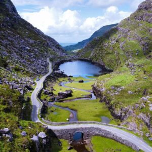 Winding mountain road beside lake in scenic Irish valley